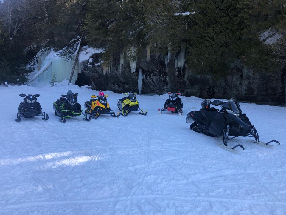 Group of snowmobiles parked by ice cliffs in Ontario